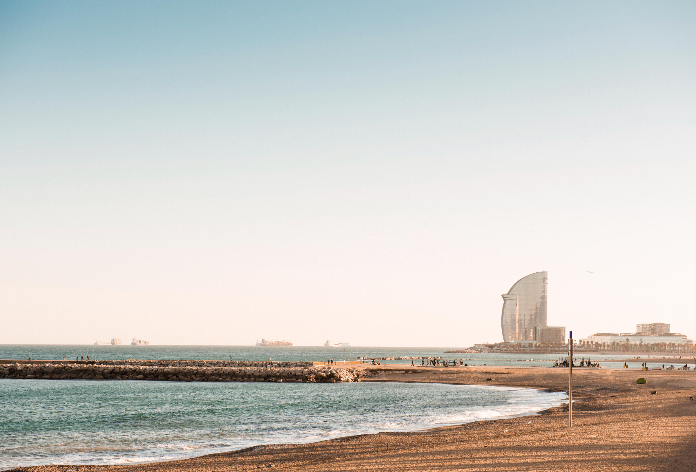 Barcelona beach Barceloneta beach on a clear morning. there is an empty beach, still blue water and clear blue sky's. The W hotel is in the background